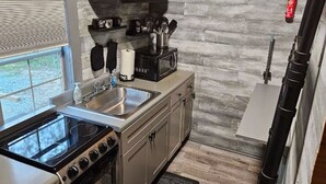 A kitchen with a stove, sink, microwave, and cabinets. - The Cozy Cove Cabin, in Townville, on Lake Hartwell. (Townville)