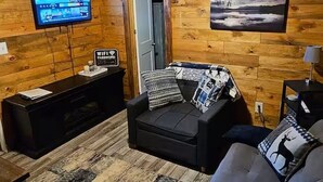 A cozy room with a wooden interior, a sofa, a television, and a sign indicating WiFi availability. - The Cozy Cove Cabin, in Townville, on Lake Hartwell. (Townville)