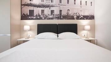 Habitación de hotel con una cama, dos mesitas de noche, dos lámparas y un cartel grande en la pared.