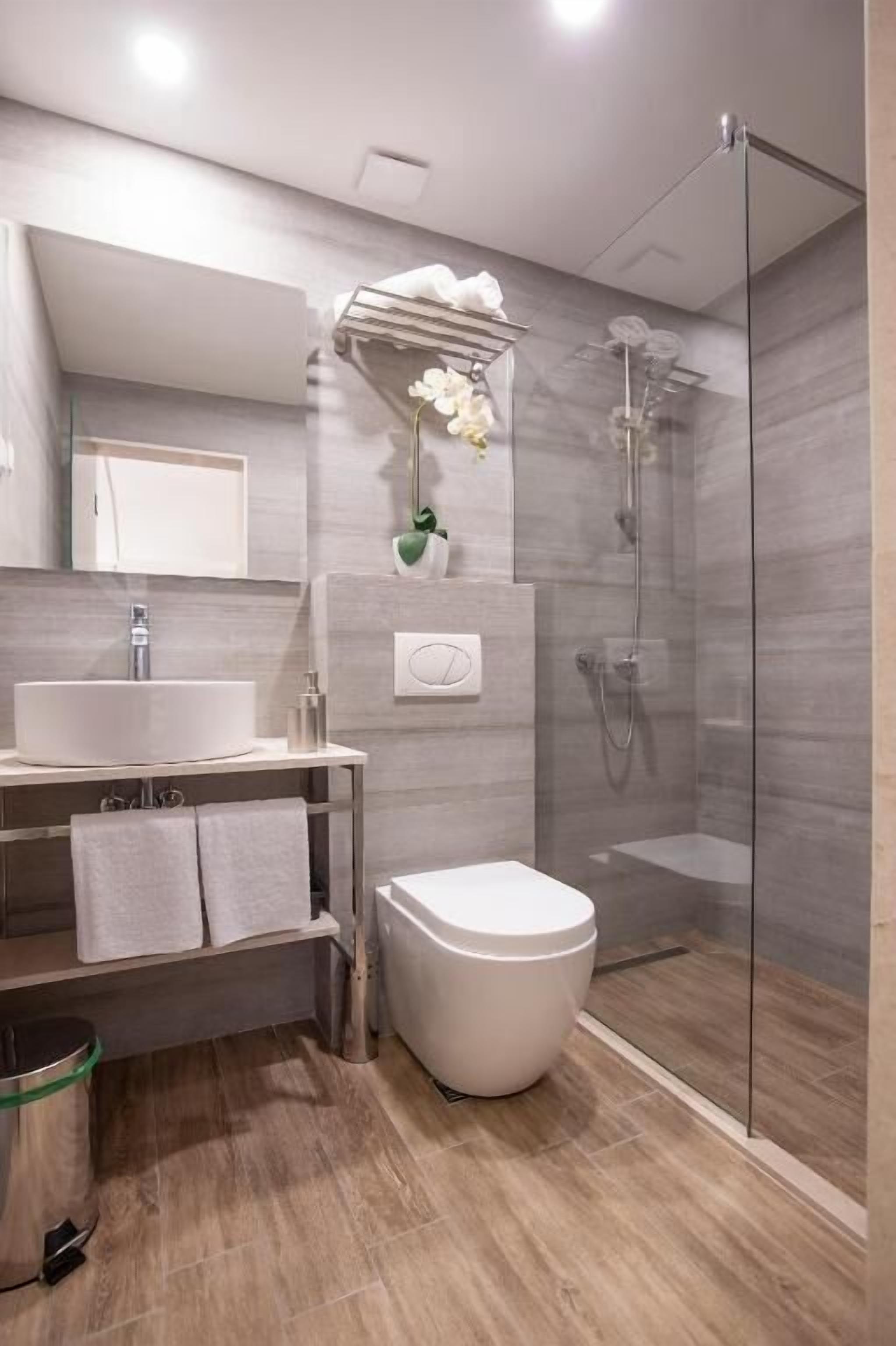 A modern bathroom with a glass-enclosed shower, a white sink, and a toilet.