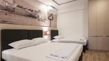 A hotel room with two beds, a wall mural, a wardrobe, and a bedside lamp.
