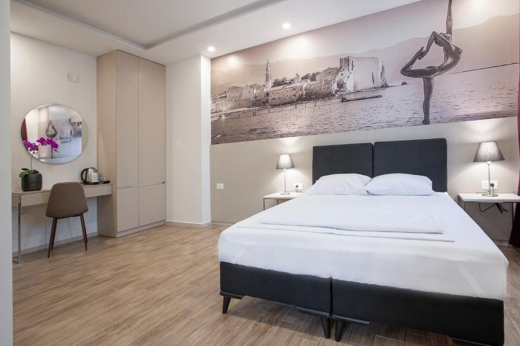 A hotel room with a bed, desk, chair, and a large wall mural.