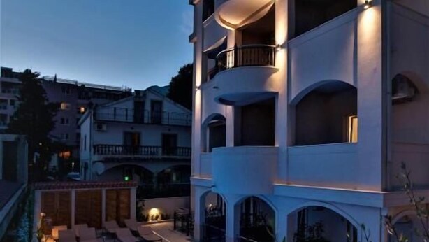 A multi-story building with a swimming pool, balconies, and outdoor seating. - Casa Mia (Budva)