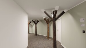 Um corredor com vigas de madeira aparentes, piso coberto de carpete e uma porta com a inscrição 'suite 207'.