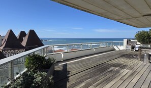 Une terrasse en bois offrant une vue sur l’océan et les bâtiments situés sur la côte.
