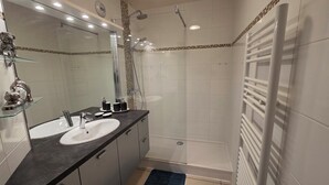 A modern bathroom with a glass shower enclosure, a large mirror, and a dark countertop. - Panoramic view and terrace in Biarritz (Biarritz)
