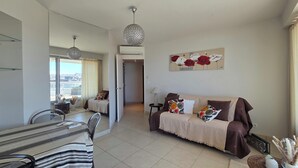 A living room with a sofa, a dining table, and chairs. There is a painting on the wall and a ceiling light fixture. - Panoramic view and terrace in Biarritz (Biarritz)