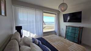 A bedroom with a bed, a dresser, a TV, and a window with a view of the beach. - Panoramic view and terrace in Biarritz (Biarritz)