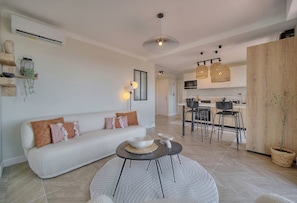 A modern living room with a sofa, coffee table, and dining area with chairs and a kitchen in the background. - Panoramic sea view in Cannes (Cannes)