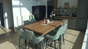 Moderni keittiö, jossa on puinen keittiösaareke, baarituolit ja ruokapöytä.