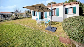 Ein Haus mit Terrasse, einem Tisch und Stühlen sowie einem großen Sonnenschirm.