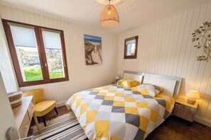 Ein Schlafzimmer mit Bett, Stuhl, Schreibtisch, Lampe und einem Fenster mit Jalousien.