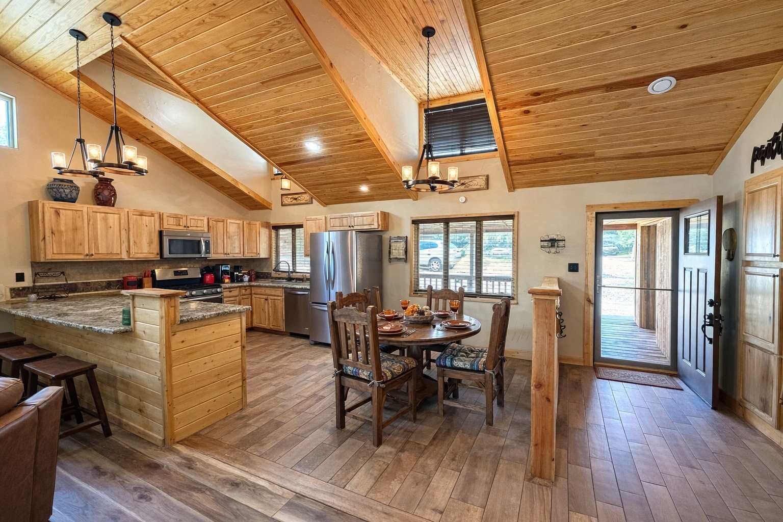 Une cuisine spacieuse dotée de meubles en bois, d’un îlot central et d’un coin repas avec une table et des chaises en bois.