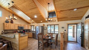 Une cuisine spacieuse dotée de meubles en bois, d’un îlot central et d’un coin repas avec une table et des chaises en bois.