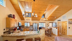 Une cuisine spacieuse dotée de meubles en bois, d’un plan de travail en granit et d’un coin repas avec une table et des chaises en bois.