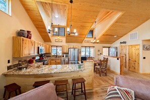 A spacious kitchen with wooden cabinets, a granite countertop, and a dining area with a wooden table and chairs.
