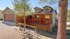 Une cabane en bois à deux étages, dotée d’un porche à l’avant et d’un garage.