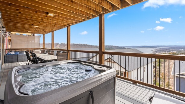 Un jacuzzi en una terraza de madera con vistas a un lago y edificios.