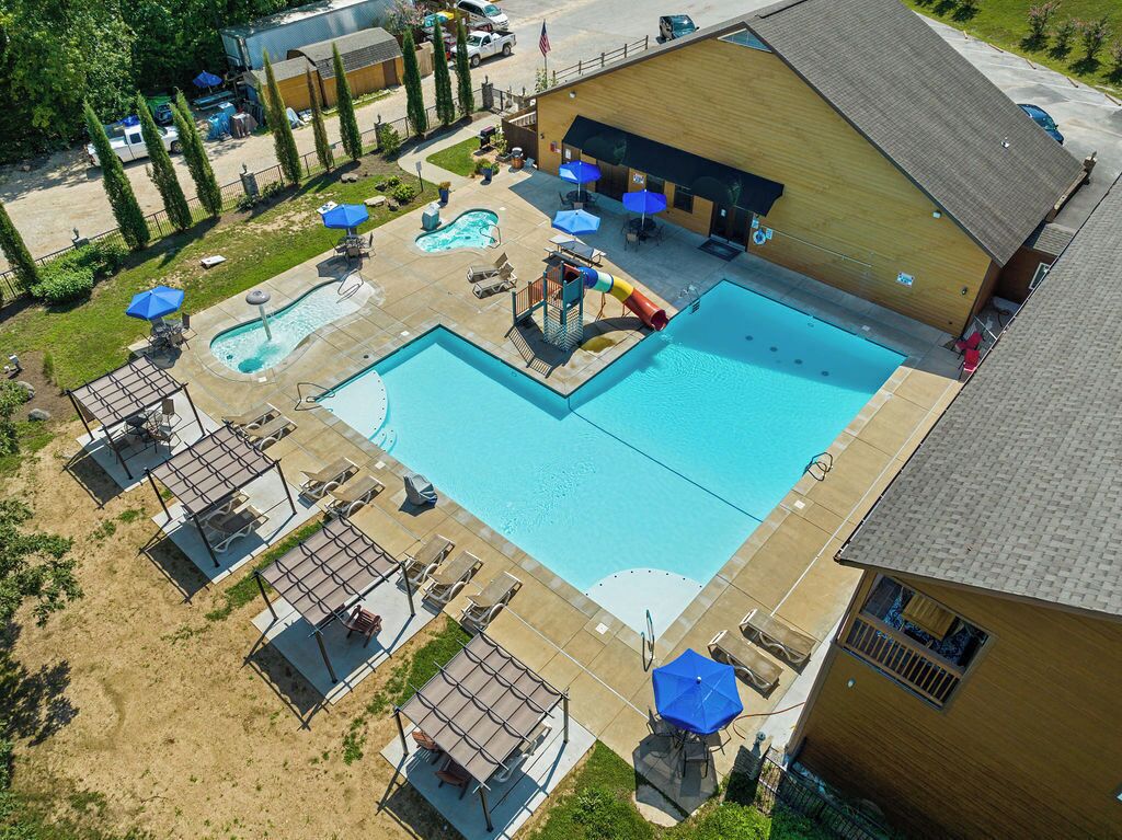A large swimming pool with a slide, sun loungers, and umbrellas.