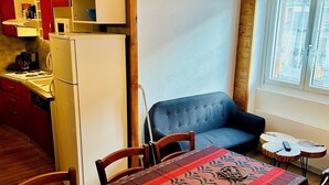 A dining area with a table set for four, a blue sofa, and a kitchen in the background. - Spacious apartment in village center, shops 2 steps away. (Val-Cenis)