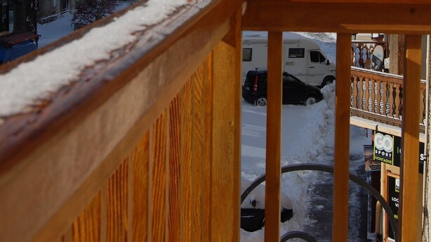 A mountain town with snow-covered buildings, a wooden balcony, and a snow-covered street. - Spacious apartment in village center, shops 2 steps away. (Val-Cenis)