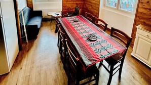 A cozy kitchen with wooden walls, a dining table with chairs, a sofa, and a TV mounted on the wall. - Spacious apartment in village center, shops 2 steps away. (Val-Cenis)