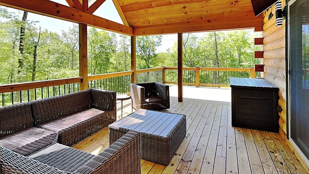 Une terrasse couverte, aménagée avec des meubles en osier et dotée d’un barbecue.