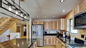 Une cuisine moderne avec des meubles en bois, des appareils en acier inoxydable, un plan de travail en granit et une cuisinière intégrée.