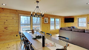 Un intérieur en bois comprenant une table à manger, des chaises, un canapé et un téléviseur fixé au mur.