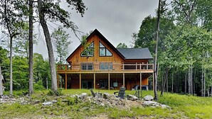 Une grande cabane en bois dotée d’un balcon, entourée d’arbres.