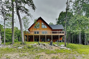 A large wooden cabin with a balcony, surrounded by trees. - Grace Mountain Cabin (McHenry)