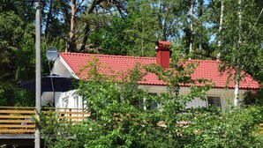 A house with a red roof, a satellite dish, and a wooden deck.