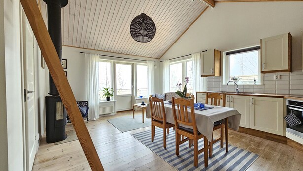 A cozy kitchen with wooden cabinets, a dining table with chairs, and a large window.
