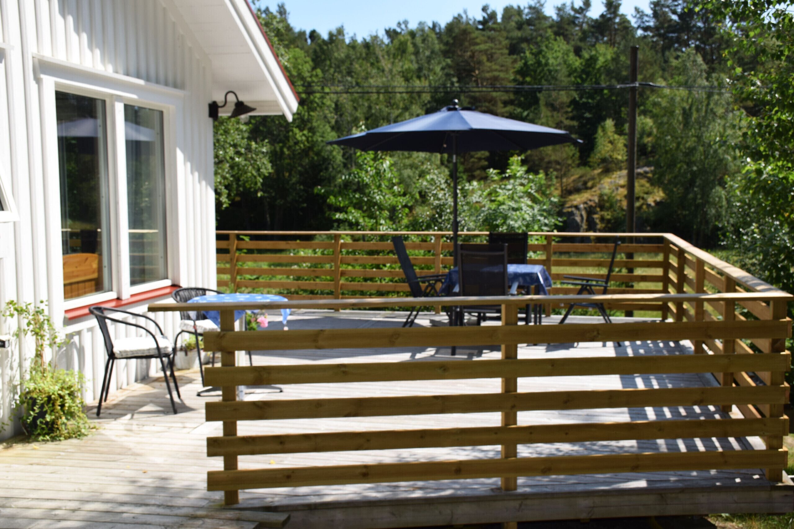 A wooden deck with outdoor furniture, a table, and an umbrella.
