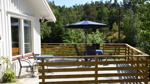 A wooden deck with outdoor furniture, a table, and an umbrella.