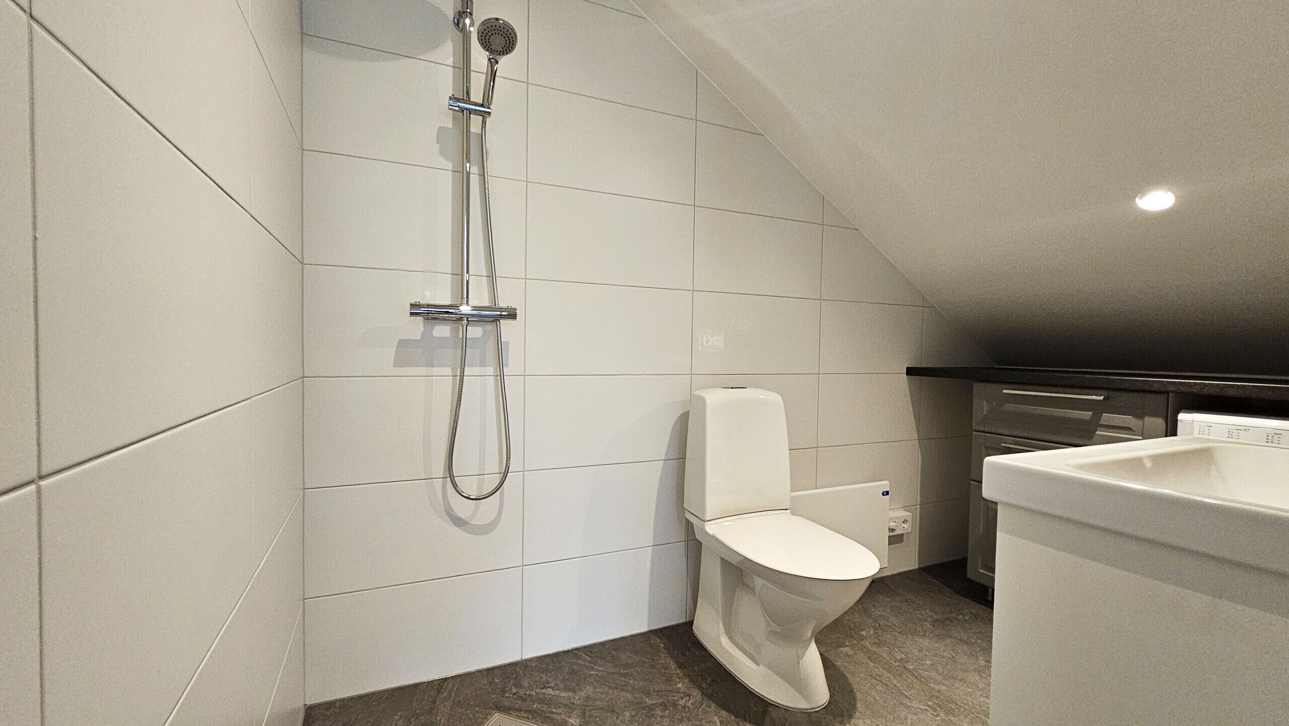 A modern bathroom with a shower, toilet, and sink.