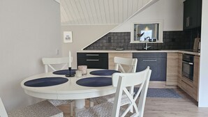 Uma cozinha moderna com mesa de jantar branca, armários pretos e painel de fundo cinza.