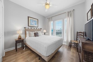 A bedroom with a bed, nightstands, a desk, a television, and a ceiling fan. - 🪸Beachfront 4BR Home | Community Pool | Gulf Views | Coral Reef East🪸 (Gulf Shores)