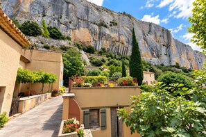 A residential area with a prominent cliff, terraced houses, and a variety of vegetation. - Charming House with Stunning Views and Rooftop Terrace (Lioux)