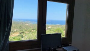 A room with a large window, a computer monitor, and a keyboard on a wooden desk. - Apartment Sunrise 23 (San Pantaleo)