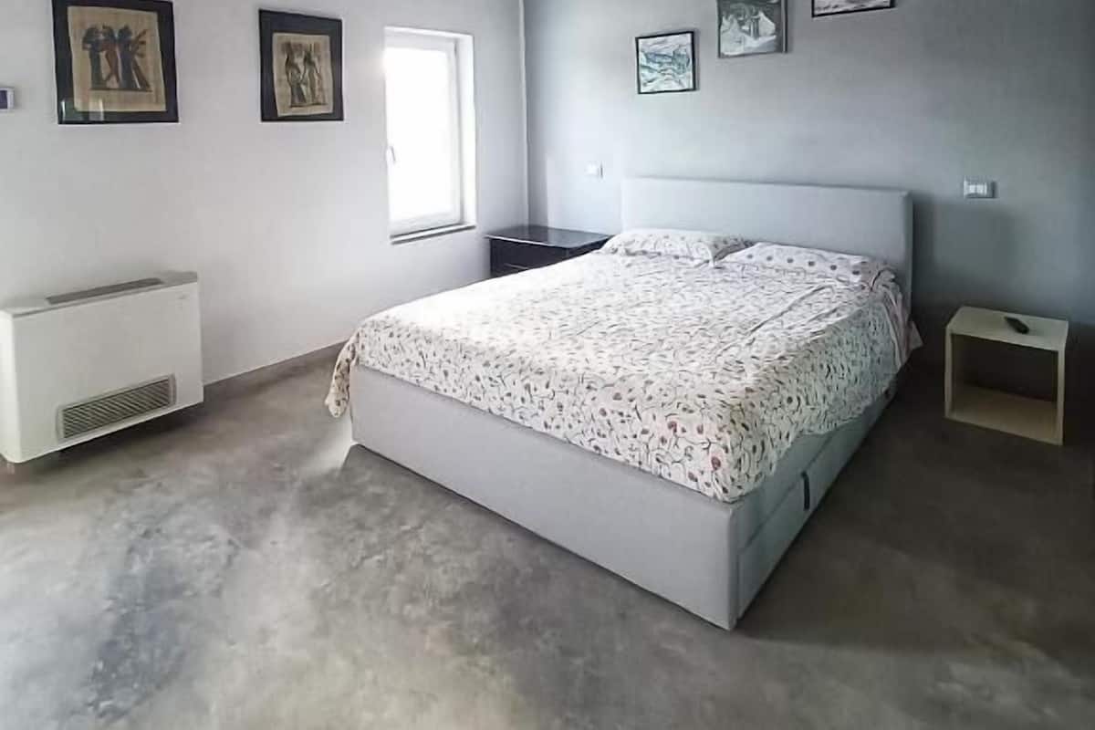 A bedroom with a bed, a window, and a radiator.