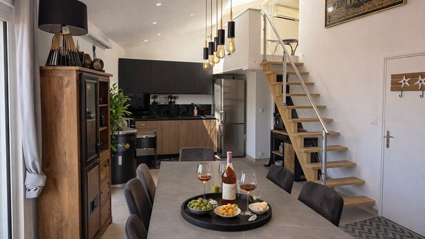 Une cuisine moderne avec un coin repas, un escalier et une œuvre d’art accrochée au mur.