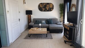 Un salon moderne avec un canapé gris, une table basse, un téléviseur et un élément décoratif mural.