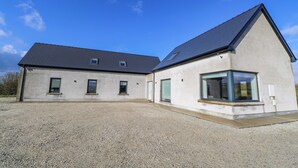 A modern building with a gravel driveway, a sloped roof, and multiple windows.