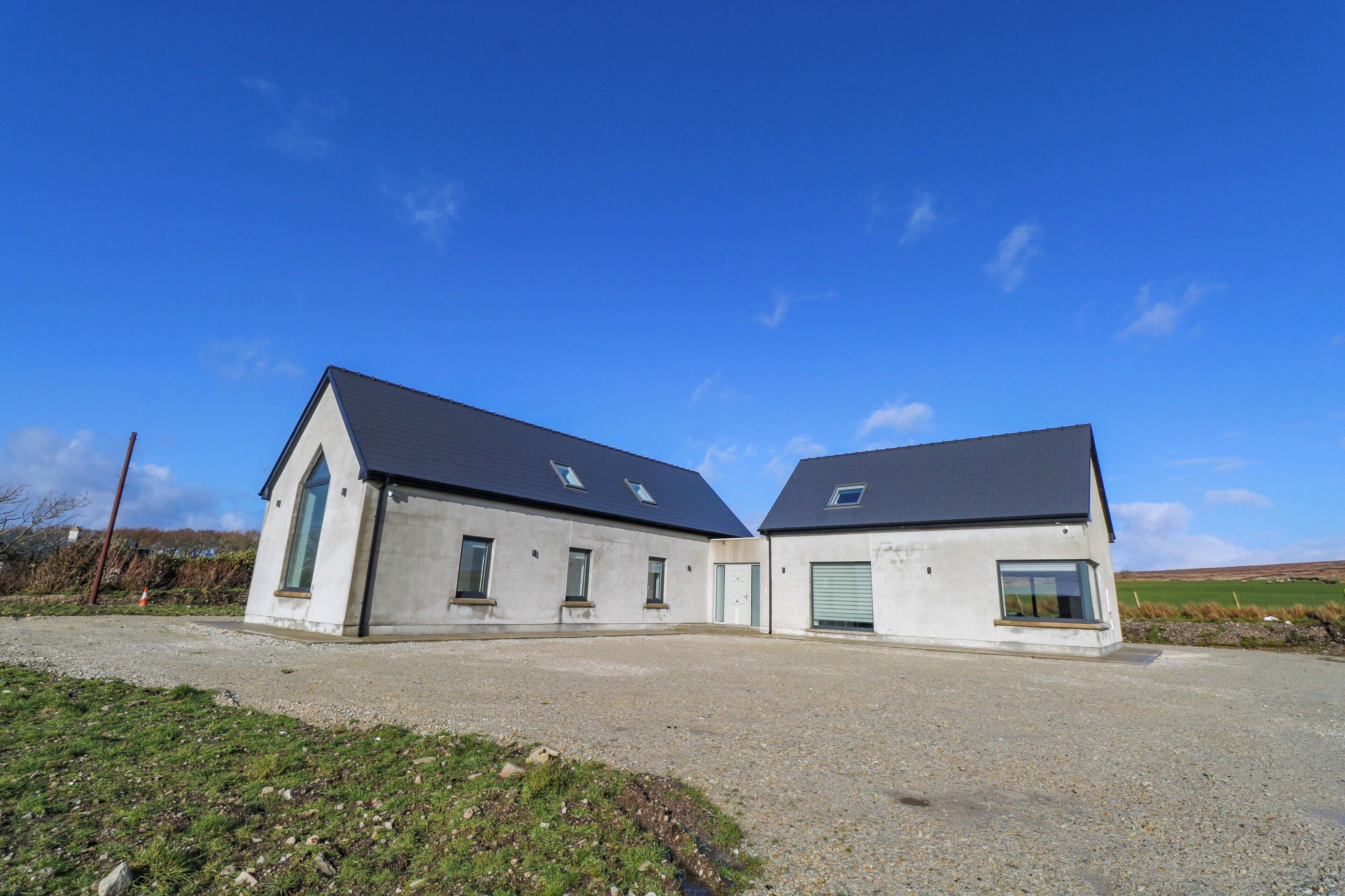 A two-story building with a gravel driveway and a grassy area in front.