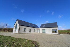 A two-story building with a gravel driveway and a grassy area in front.
