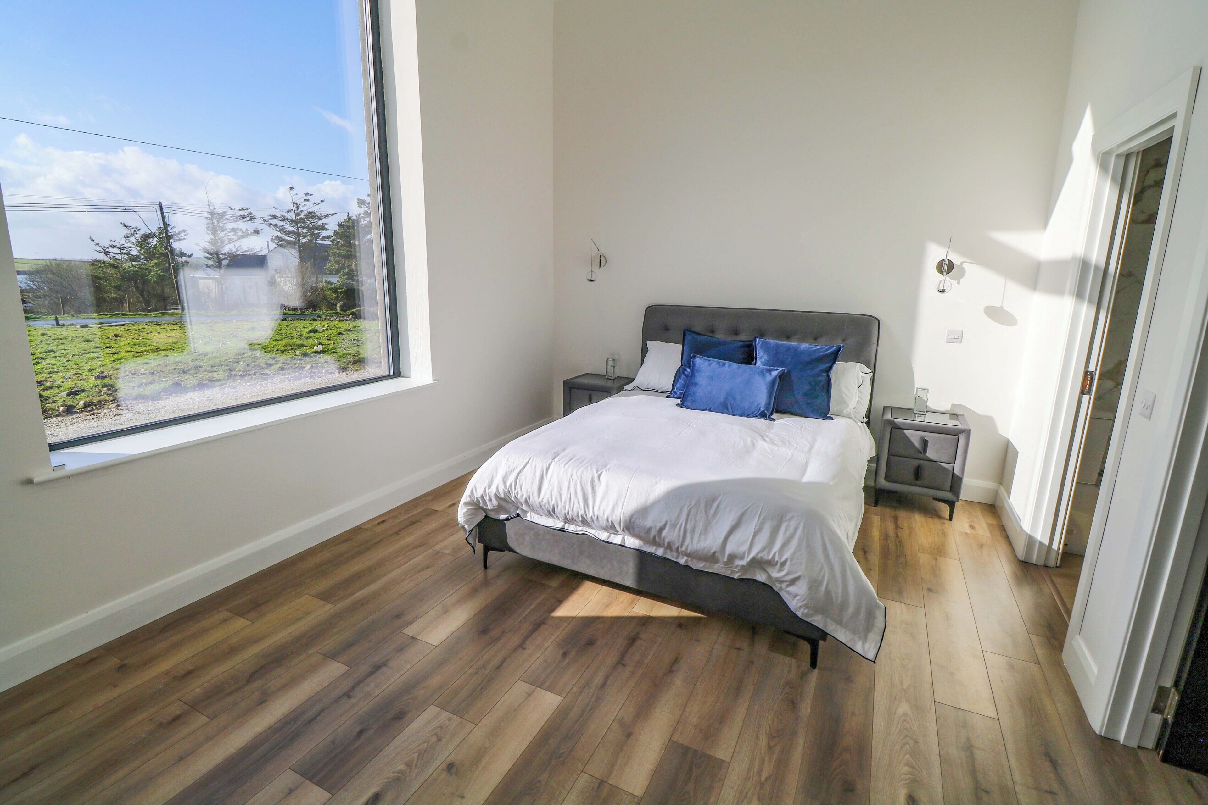 A bedroom with a bed, bedside tables, a window, and a door.
