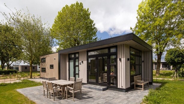 Ein modernes Haus mit Terrasse, einem Esstisch und Stühlen.