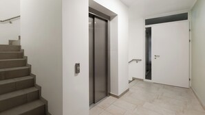 A modern interior with a staircase, elevator, and a door leading to another room. - Limehome Wels Old Town (Wels)