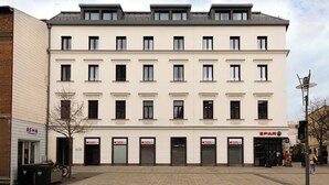 A multi-story building with a row of shops on the ground floor, including a Spar supermarket. - Limehome Wels Old Town (Wels)